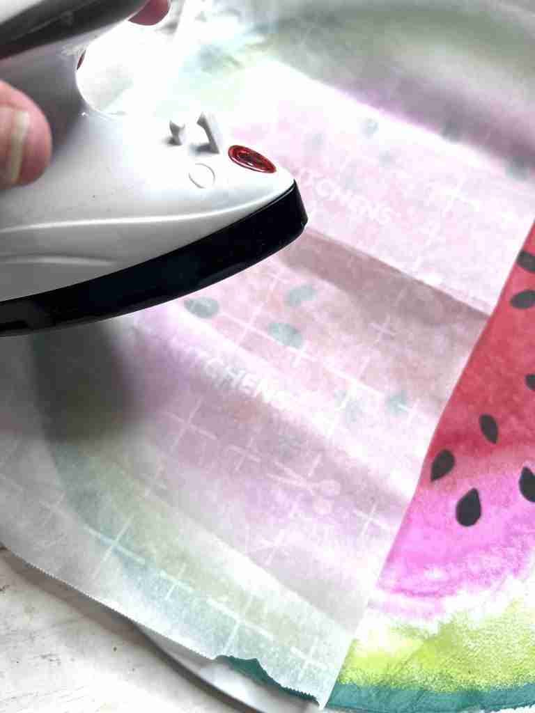 ironing napkin onto pizza pan with mini iron