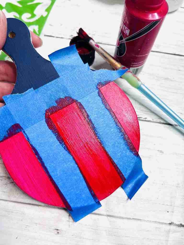cutting board with painter's tape applied and red stripes painted