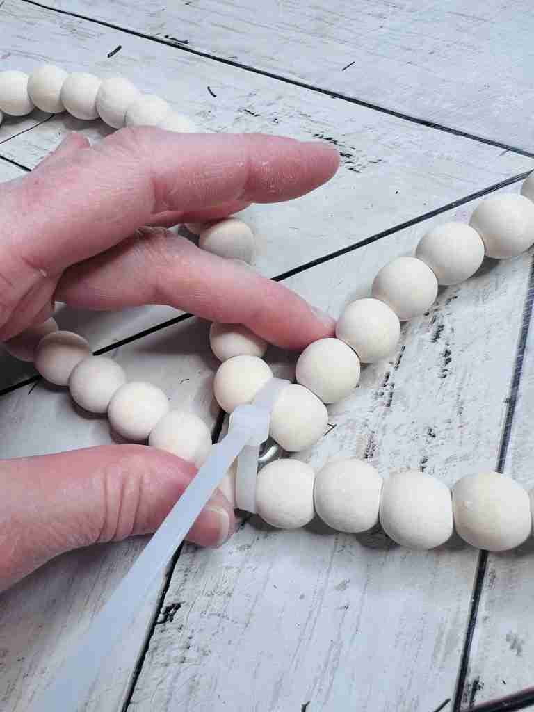 beaded heart wreath with top middle pulled down to bottom and secured with zip tie