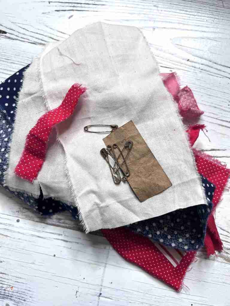 material scraps, rusty safety pins, paper tag