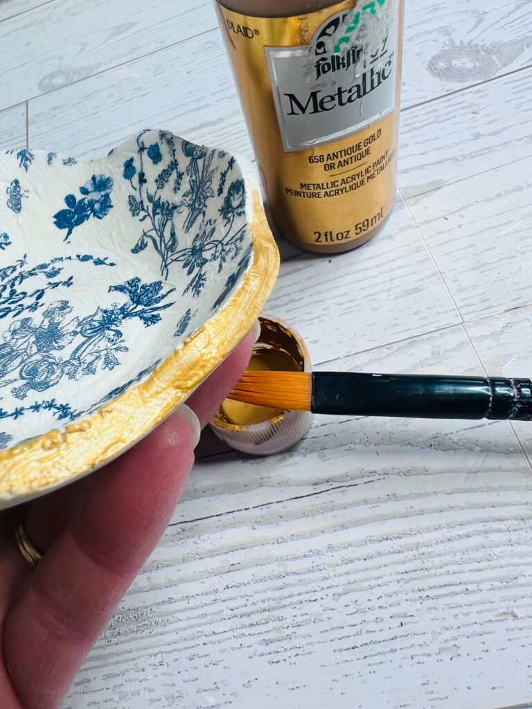 adding gold paint to edges and bottom of clay bowl