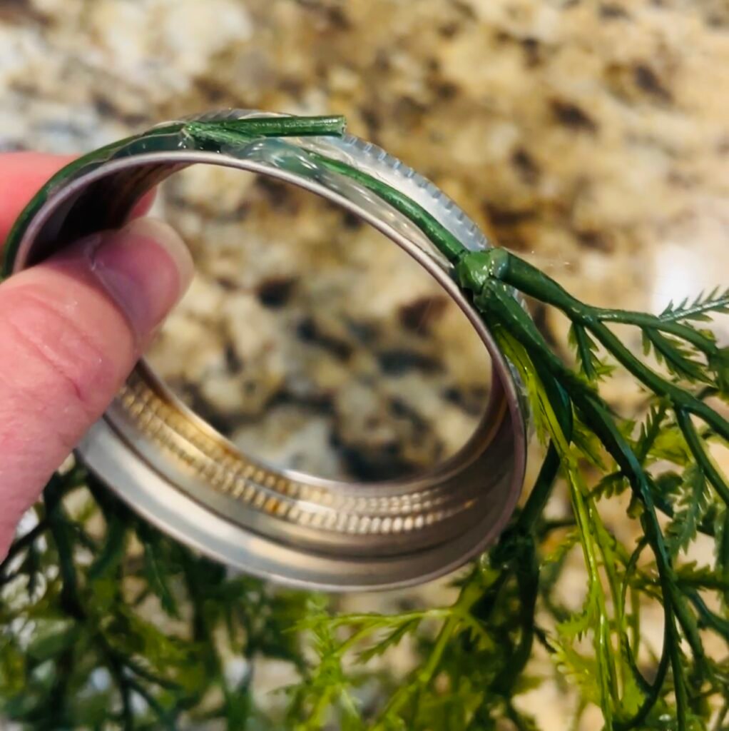 old canning ring with greenery hot glued onto outside
